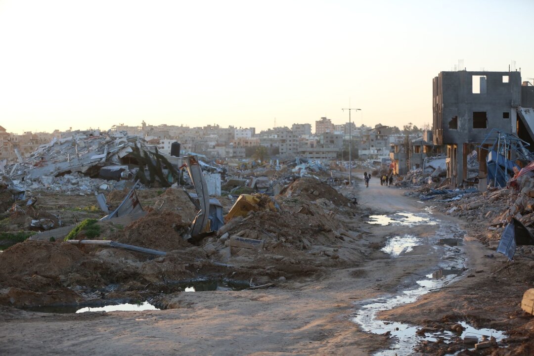 Sechs Monate Gaza-Krieg in Zahlen - Menschen gehen an Trümmern und Ruinen auf einer Straße im Flüchtlingslager Al-Maghazi im Zentrum des Gazastreifens vorbei.