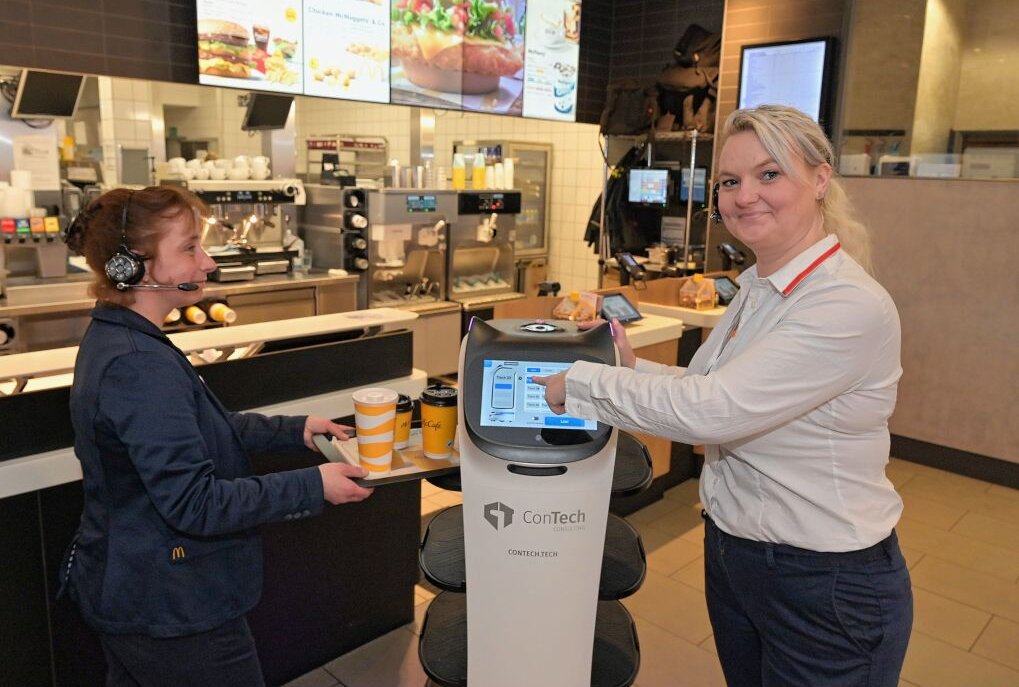 Service-Roboter ist 14 Tage bei McDonald's in Aue im Einsatz gewesen - Ivetta Müller von der Gästebetreuung des Restaurants (li.) und Schichtführerin Jenny Lang (re.) mit dem Service-Roboter, der jetzt 14 Tage bei McDonald's in Aue im Einsatz gewesen ist. Foto: Ralf Wendland