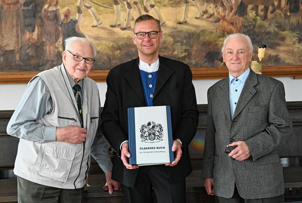 Lothar Wetzel (li.) und Walter Pflugbeil (re.) haben sich als erste ins Silberne Buch der Bergstadt Schneeberg eingetragen, das Bürgermeister Ingo Seifert (Mitte) hier in Händen hält. Foto: Ramona Schwabe