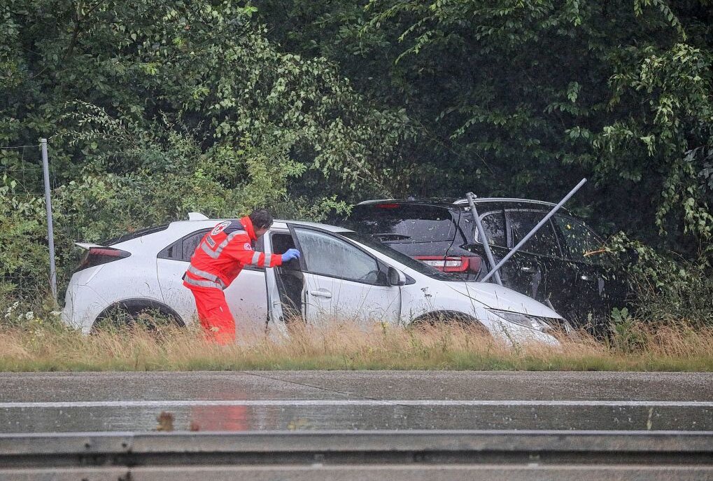 Starkregen führt zu mehreren Unfällen auf A4 bei Glauchau - Ein schwarzer Renault hatte sich überschlagen und ist neben der Autobahn zwischen Bäumen zum stehen gekommen. Kurze Zeit später krachte ein weiterer PKW in das Fahrzeug. Foto: Andreas Kretschel