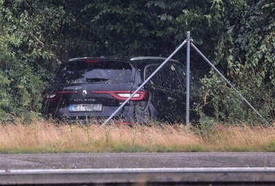Starkregen führt zu mehreren Unfällen auf A4 bei Glauchau - Ein schwarzer Renault hatte sich überschlagen und ist neben der Autobahn zwischen Bäumen zum stehen gekommen. Kurze Zeit später krachte ein weiterer PKW in das Fahrzeug. Foto: Andreas Kretschel
