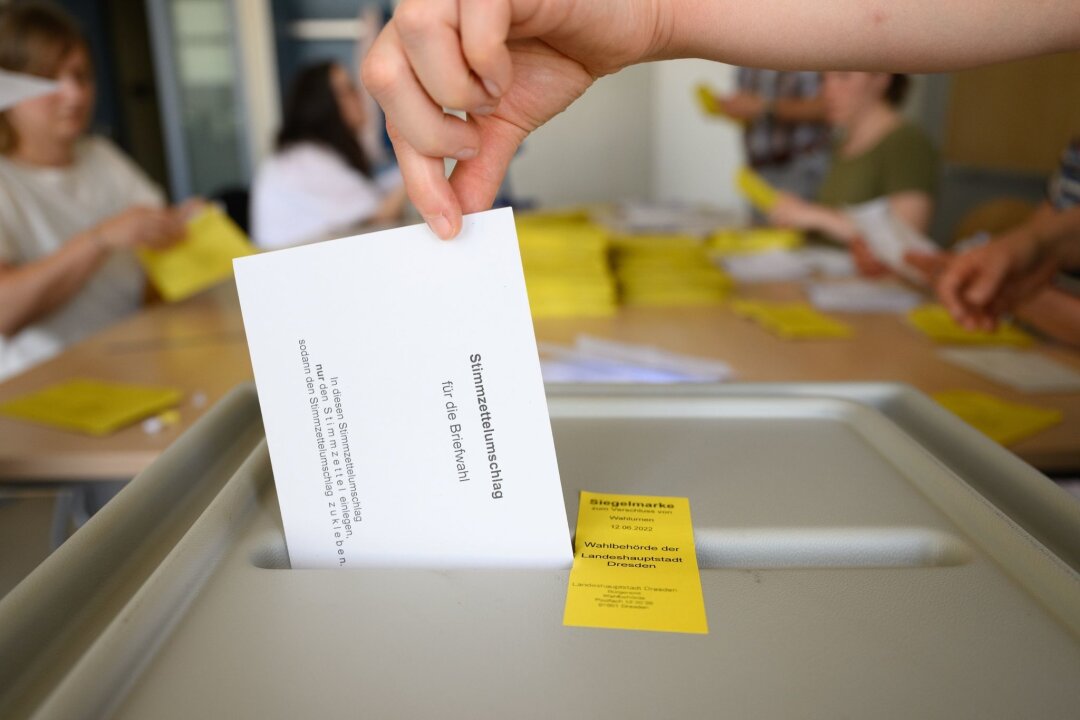 Tausende melden sich als Wahlhelfer für das Superwahljahr - Ein Stimmzettelumschlag für die Briefwahl wird in eine Wahlurne geworfen.