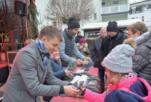 Thalheimer Weihnachtsmarkt war gut besucht - Nach dem Stollenanschnitt ist die süße Leckerei unter den Weihnachtsmarktbesuchern verteilt worden - vorn Bürgermeister Nico Dittmann. Foto: Ralf Wendland