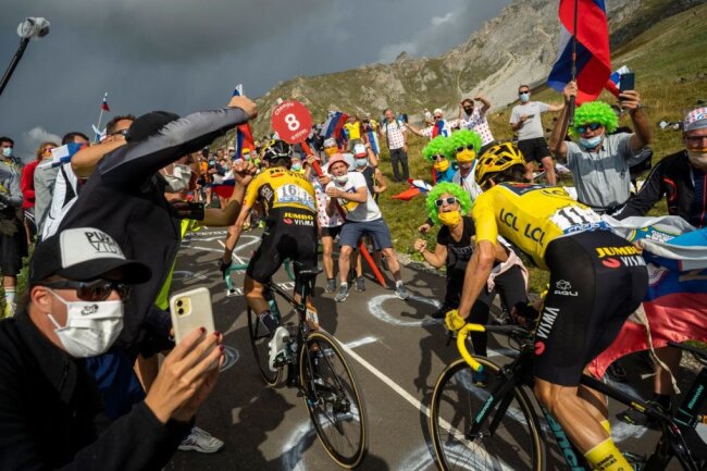 Ein Duell der Tour de France von 2020 zwischen Sepp Kuss (Nummer 16) and Primos Roglic (Nummer 11) am Col de la Loze in Meribel, Frankreich. Aufgrund der Corona-Beschränkungen in jenem Jahr wurde die Anwesenheit von Fans an der Strecke begrenzt - beziehungsweise deutlich "erschwert".
