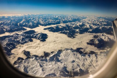 Turbulenzen: Die Ursachen und was Flugpassagiere tun können - Blick auf verschneite Berggipfel aus einem Flugzeug heraus: Gerade ist das Wetter über den Alpen gut. Das kann sich aber schnell ändern.