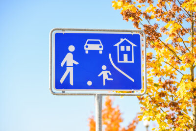 Überhöhte Geschwindigkeit - Das blaue Schild für einen verkehrsberuhigten Bereich darf nicht mit einer Spielstraße verwechselt werden. Letztere besitzen ein eigenes Straßenschild und dort gilt totales Fahrverbot. Bild: stock.adobe.com © schulzfoto