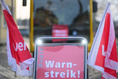 Update: Unbefristete Streiks im sächsischen Nahverkehr vorerst vom Tisch? - Ein Schild "Warnstreik" steht vor einem Bus der Dresdner Verkehrsbetriebe (DVB).