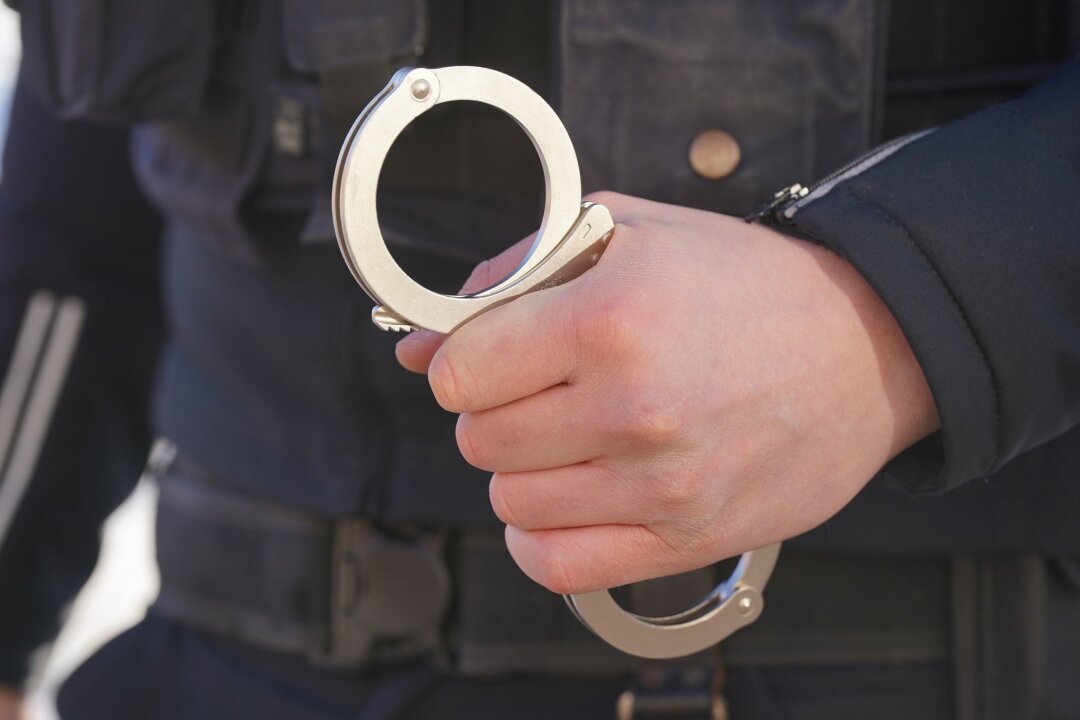 Verdächtige nach Angriff auf Journalist in Leipzig ermittelt - Ein Polizist hält Handschellen in der Hand.