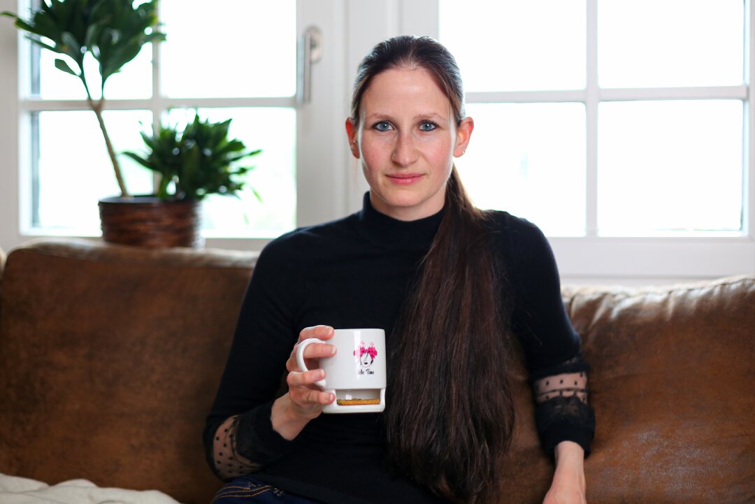 Diana Drechsel sitzt mit einer Tasse Tee auf dem Sofa.