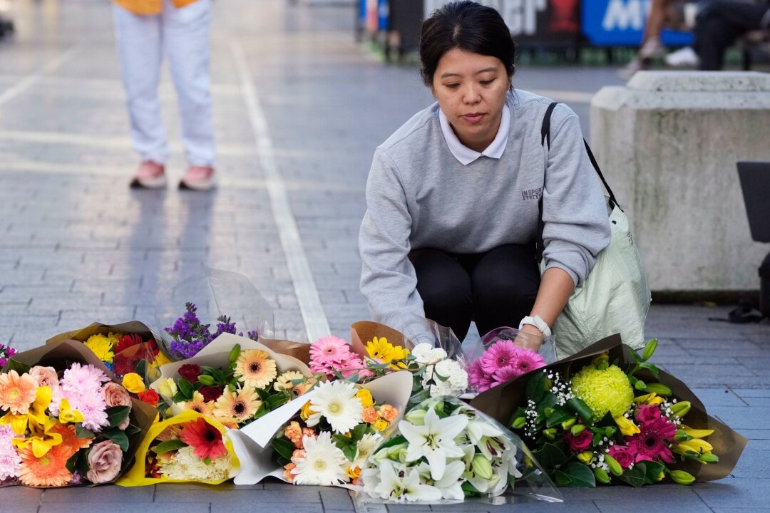 "Viele Leben gerettet" - Polizistin als Heldin gefeiert - Eine Frau bringt Blumen zu einer improvisierten Gedenkstätte an der Bondi Junction.
