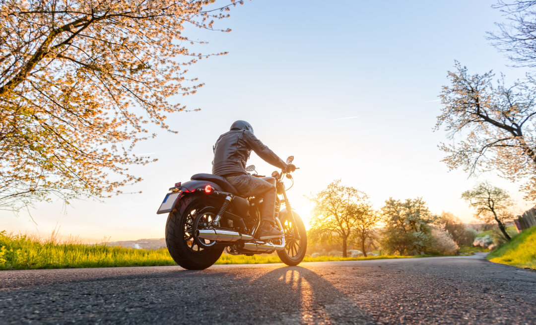 Sonnenuntergang eines Frühlingstages und im Vordergrund ist ein Motorradfahrer zu sehen.