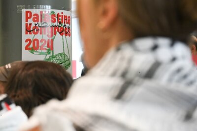 Vorgehen gegen "Palästina-Kongress" in Berlin kritisiert - Teilnehmer sitzen vor Beginn des Palästina-Kongress 2024 im Veranstaltungsraum vor einem Plakat des Kongresses.