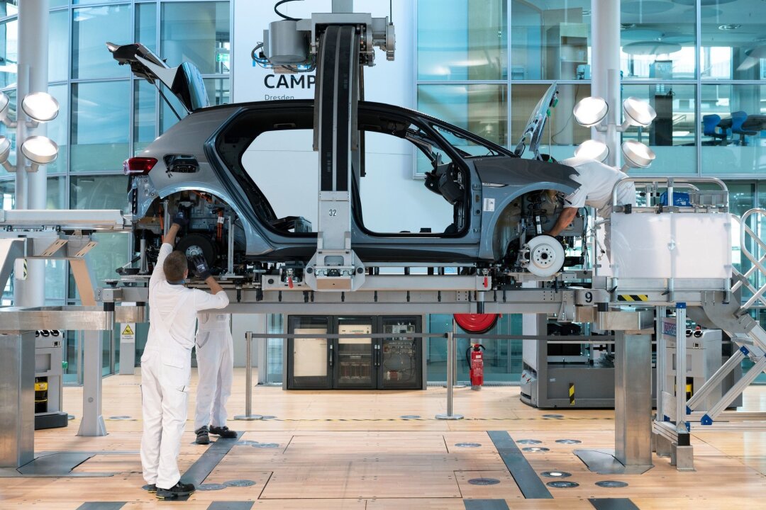 VW erwägt Einstellung der Autoproduktion in Dresden - Mitarbeiter montieren in der Gläsernen Manufaktur von Volkswagen die Karosserie und den Antriebsstrang eines VW ID.3.
