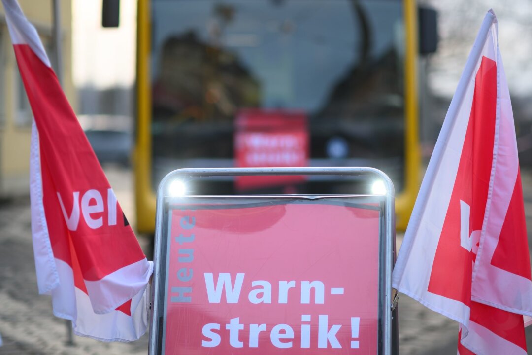 Warnstreiks im sächsischen Nahverkehr angelaufen - Ein Schild „Warnstreik“ steht vor einem Bus der Dresdner Verkehrsbetriebe (DVB) während des Warnstreiks im öffentlichen Nahverkehr.
