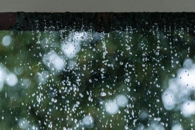 Warum verstopfte Regenrinnen so schlimm sind - Statt zum Abfluss schießt das Regenwasser während eines Unwetters an einer verstopften Regenrinne hinunter und sucht sich seinen Weg.