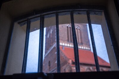 Wismar: Im "Kittchen" sind bald Zimmer frei - Durch ein vergittertes Hotelzimmerfenster in der ehemalige Jugend-Arrestanstalt können nach dem Umbau zum Hostel "Das Kittchen" Übernachtungsgäste zum St. Marienkirchturm schauen.