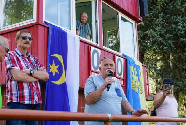 Vor den Flaggen der beiden Partnerstädte spricht Jürgen Hetzner über die jahrzehntelange Beziehung. Foto: Andreas Bauer